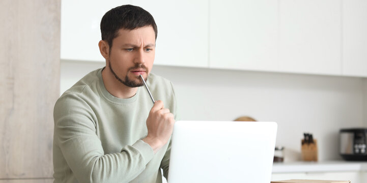 Man thinking while using laptop at home