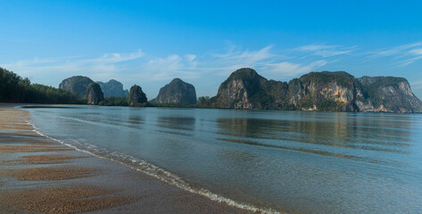 Obraz premium Tropical beach with calm sea and limestone mountains under a clear blue sky