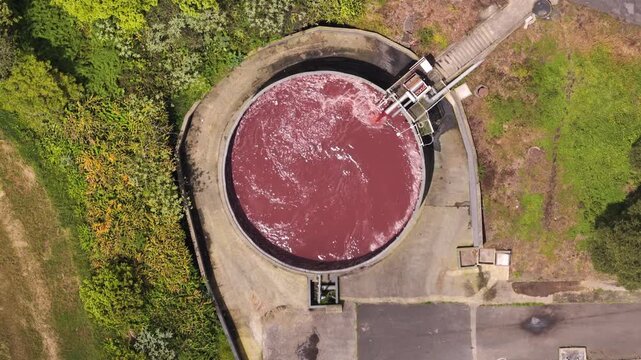Aerial view of a circular industrial tank containing reddish liquid at a processing facility in Rabo de Peixe, Acores, Portugal.
