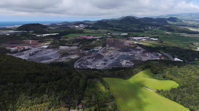 Aerial view of the Tecnovia Acores quarry site featuring industrial excavation areas surrounded by lush green hills and rural landscape in Rabo de Peixe, Acores, Portugal.