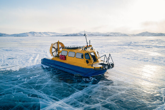 Aerial view on a hovercraft parked on the beautiful cracked ice of the lake Baikal. Winter Baikal, frozen lake. Amazing winter landscape.