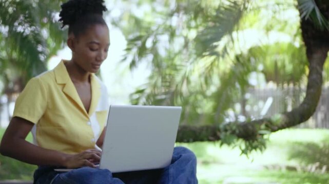 Young woman typing on laptop computer in park