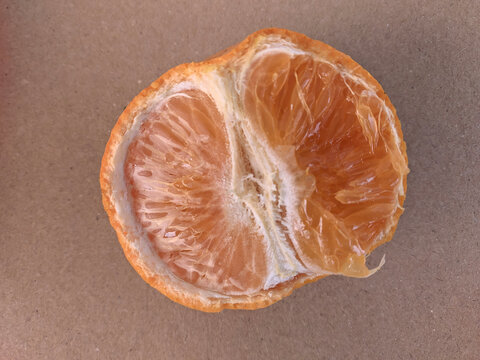 Top view of a peeled halved mandarin orange showing fresh juicy tecture on a brown background.