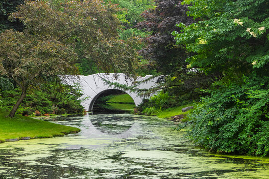 White bridge arching over green pond water in Dow Gardens, Midland, Michigan