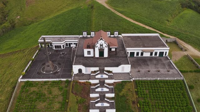 Aerial view of the historic Chapel of Nossa Senhora da Paz with its iconic staircase and surrounding green landscape in Vila Franca do Campo, Acores, Portugal.