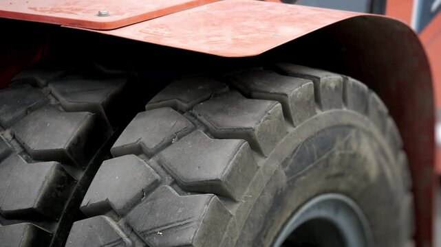 Heavy-duty forklift tires with deep tread pattern in an industrial warehouse. Close-up of warehouse equipment designed for material handling and logistics operations.