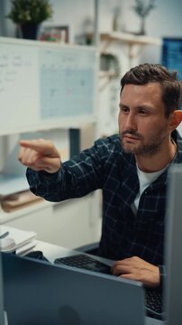 Vertical Screen : Young Caucasian male programmer writes code using multiple screens in home office. AI development, cybersecurity, network database system, software engineering, remote tech startup.