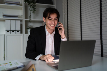 Fototapeta premium Caucasian businessman talking phone while using laptop working in office. 