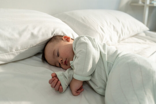 A peaceful baby boy sleeping soundly on bed in cozy bedroom at home.