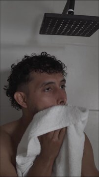 Hispanic male drying himself with a towel after showering