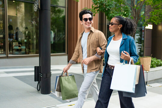 Latino man and Black woman walking outdoors while shopping in the city. 