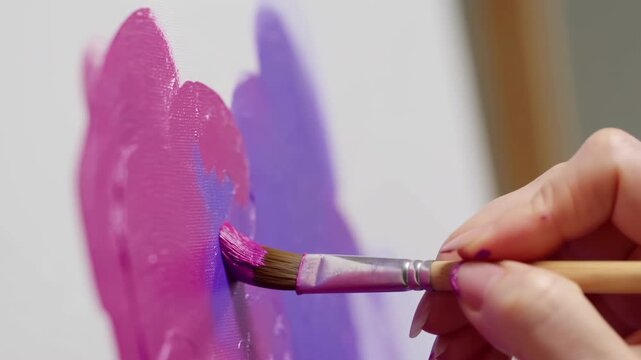 artist carefully applying pink paint to canvas in focused indoor setting with creative and focused mood, close-up of hand and brush movement, art supplies, painting tutorials, creative.