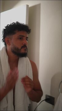 Hispanic male grooming after showering in bathroom