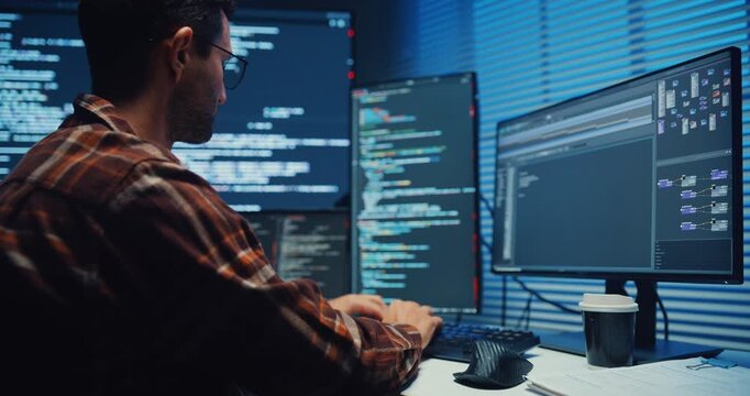 Close up young Male programmer hands typing on keyboard in dark home office at night. AI technology, cybersecurity, software developer, freelance innovation, database system, digital network concept.