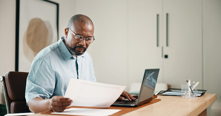 Laptop, finance and black man with documents in home for budget planning, audit or expenses. Mature person, accounting or paperwork with computer for financial assessment, review or report in house © peopleimages.com