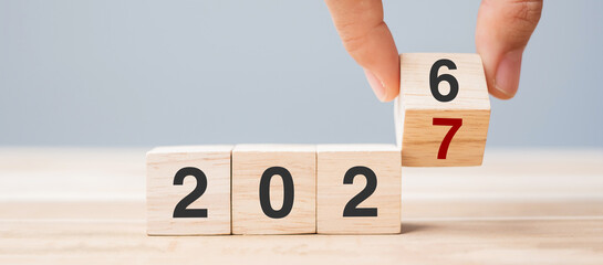 Fototapeta premium hand flip cube block 2026 to 2027 text on table. Resolution, review, strategy, end year, goal, business and New Year holiday concepts