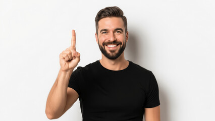 Fototapeta premium Smiling Young Man in Black T-Shirt Pointing Index Finger Up Isolated on White Background