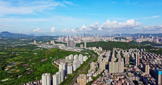 Aerial view of modern residential apartment buildings with city skyline and lush green hills in Shenzhen, China