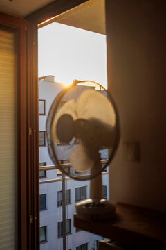 Electric fan ventilating a room on a hot summer morning.