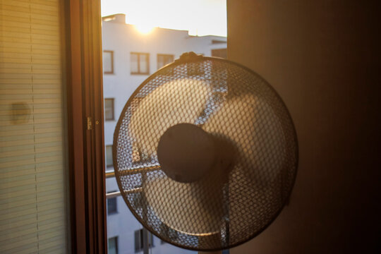 Electric fan ventilating a room on a hot summer morning.