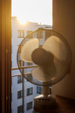 Electric fan ventilating a room on a hot summer morning.