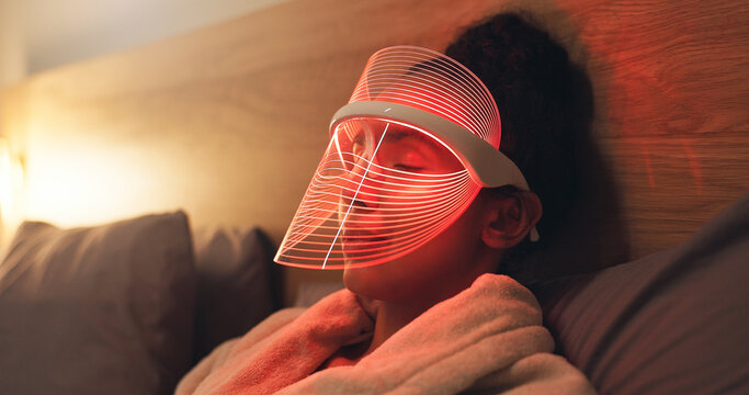 Red light, mask and woman in bedroom with skincare for beauty, wellness and collagen production. Health, relax and person in bed with LED phototherapy for dermatology or facial treatment in home