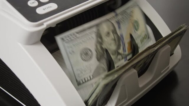 Hundred dollar bills moving through counting machine. Money counting processing. Hundred dollar banknotes motion in counting machine. Financial business success theme with dollar movement.