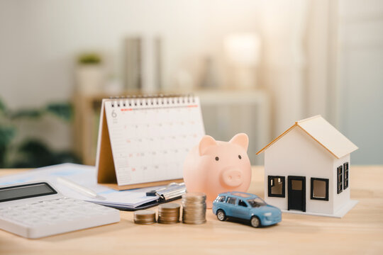 Real estate investment growth management and property asset invest features house model near pink piggy bank, while blue car sits beside rising coins with desk calendar and calculator
