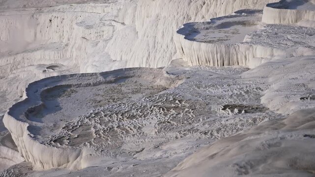 Lacy white travertine formations at hot springs of cotton castle of Pamukkale on sunny day, Turkey
