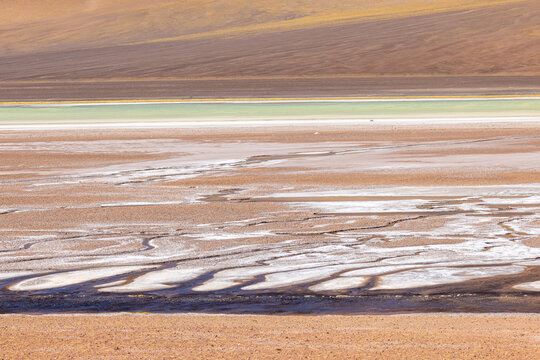 View of Salar de Aguas Calientes with its mineral-rich salt crust and vibrant turquoise water pools set against the arid desert landscape of San Pedro de Atacama, Antofagasta, Chile.