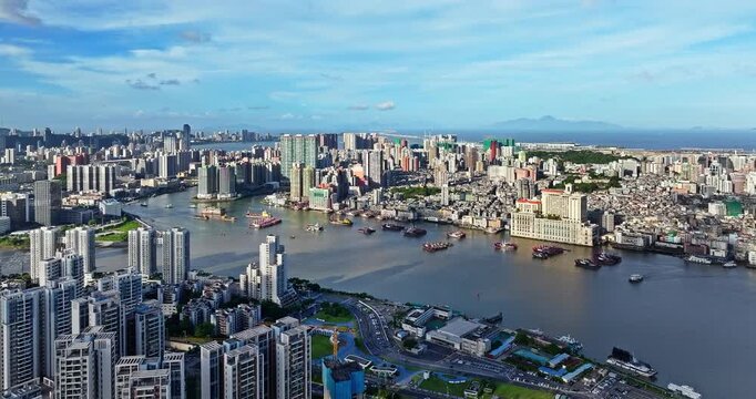 Aerial view of a busy river port with cargo ships and dense urban cityscape in Zhuhai, China