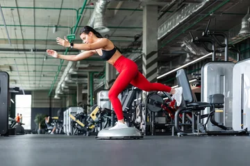 Fotobehang Sportschool Athletic woman doing single-leg deadlift balance exercise on BOSU ball at gym  © ty