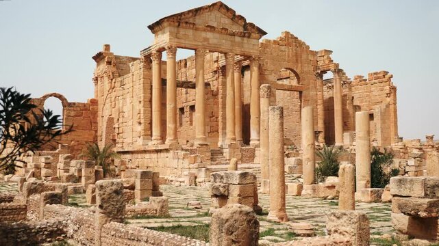 Scenic view of ancient Roman forum at Sbeitla archaeological site in Tunisia with majestical ruins of temple dedicated to Capitoline Triad - Jupiter, Juno, and Minerva on spring day