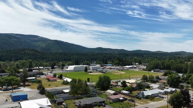 Aerial of small town Priest River Idaho in Bonner County in summer with residential streets commercial buildings and athletic fields