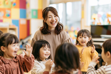 Obraz premium カラフルな保育室で手を挙げる元気な幼児たちと大笑いする日本人保育士