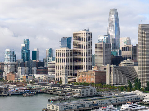 San Francisco skyline presents its modern skyscrapers and historic Ferry Building along the Embarcadero waterfront. Showing urban development and bustling harbor activities under a cloudy morning sky