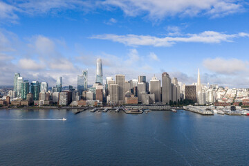Obraz premium San Francisco cityscape featuring skyscrapers, including Salesforce Tower and Transamerica Pyramid, lining the waterfront of the bay with a clear blue sky