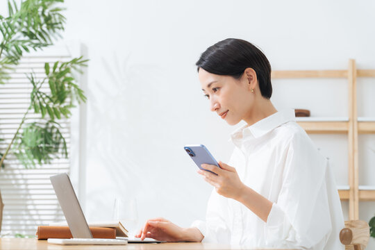 スマホとノートパソコンを使う女性。アプリ、ネットショッピング、認証、DX