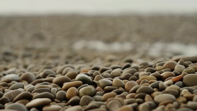 pebbles resting on sandy beach at low angle, calm and serene natural scene with brown and gray tones, for nature and beach settings, editorial and educational resources.