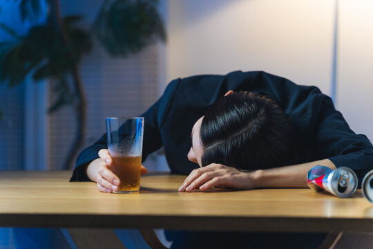 暗い部屋で酔い潰れる女性。お酒、ショック、がっかり、落ち込む、やけ酒、酔う、アルコール、居酒屋