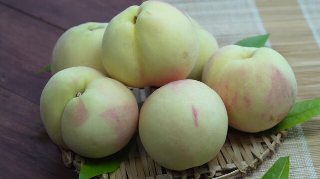 White Peaches with leaves on the wooden table, Fresh White Peach on wooden basket in wooden Background.