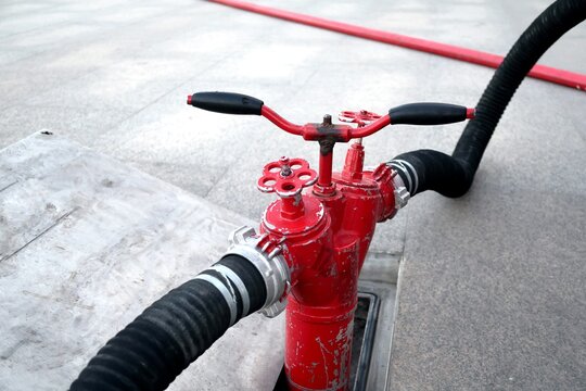 Underground fire hydrant supplying water to a fire truck through large hoses during firefighting operations. Emergency water supply system used for fire suppression and rescue response. Concept of eme