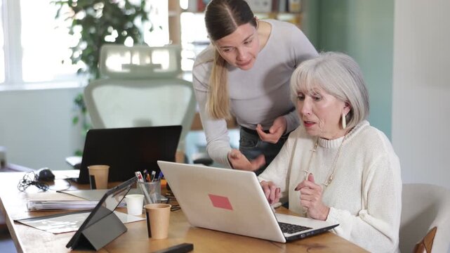 Female boss yells at senior woman employee, pensioner work at computer and reprimanded by management. Boss is dissatisfied with quality of work, is outraged by unsatisfactory competence of employee 