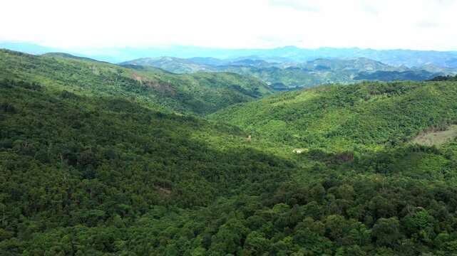 Daytime drone footage of lush, rolling green mountains and dense rainforest terrain in Laos PDR.