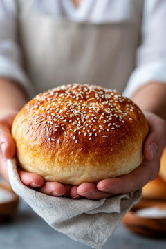 Round sesame bun gently held on linen cloth in home kitchen