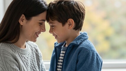 Fototapeta premium A close-up of a mother and her young son gently touching noses, sharing a loving moment with soft focus background.