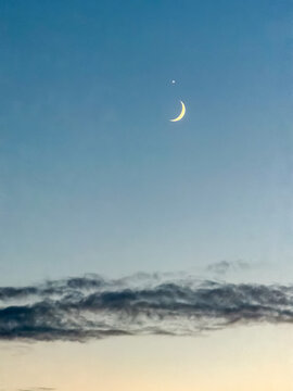 Crescent moon and Venus conjunction in twilight blue sky above soft clouds at dusk in Antwerpen, Belgi&euml;