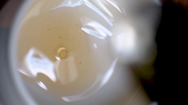 Close-up view of freshly brewed coffee being poured into a cup, creating rich foam and bubbles. Warm beverage preparation with shallow depth of field and inviting coffee texture.
