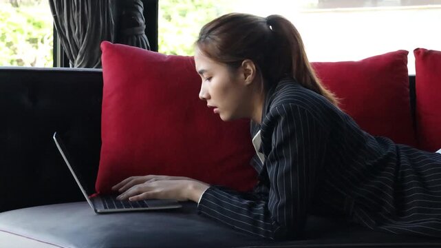 frustrated asian female professional working on sofa during daytime, upset and overwhelmed by technology issues of remote work, side view