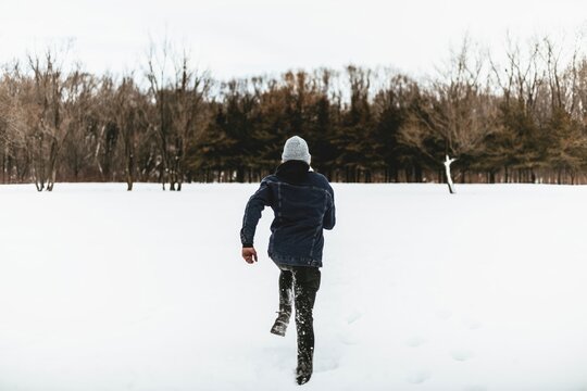 Child running in snow during winter in a forest